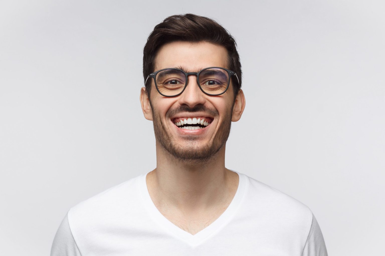Laughing out loud. Joyful young man in casual t-shirt smiles broadly, laughing, showing perfect white teeth